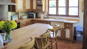 A kitchen with wooden cabinets, a large island, a sink, and a window with a view. - 4 bedroom accommodation in Dumpling Green, near Dereham (Dumpling Green, near Dereham)
