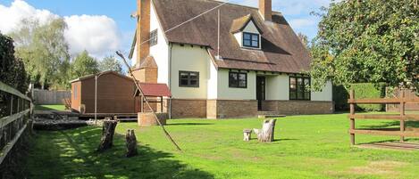 A two-story house with a sloped roof, a chimney, and a small attached shed.