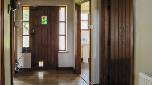 A hallway with a wooden door, a window with a stained glass design, and a white radiator. - 4 bedroom accommodation in Dumpling Green, near Dereham (Dumpling Green, near Dereham)