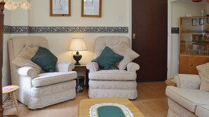 A living room with two armchairs, a small table, a lamp, and a decorative rug. - 2 bedroom accommodation in Wells-next-the-Sea (Wells-next-the-Sea)
