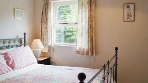 A bedroom with a bed, a nightstand, a lamp, a window with curtains, and a framed picture on the wall. - 2 bedroom accommodation in Wells-next-the-Sea (Wells-next-the-Sea)