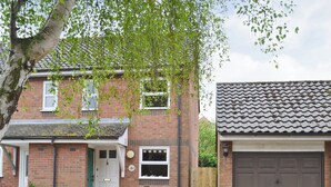 A two-story brick house with a front porch, a garage, and a garden with potted plants. - 2 bedroom accommodation in Wells-next-the-Sea (Wells-next-the-Sea)