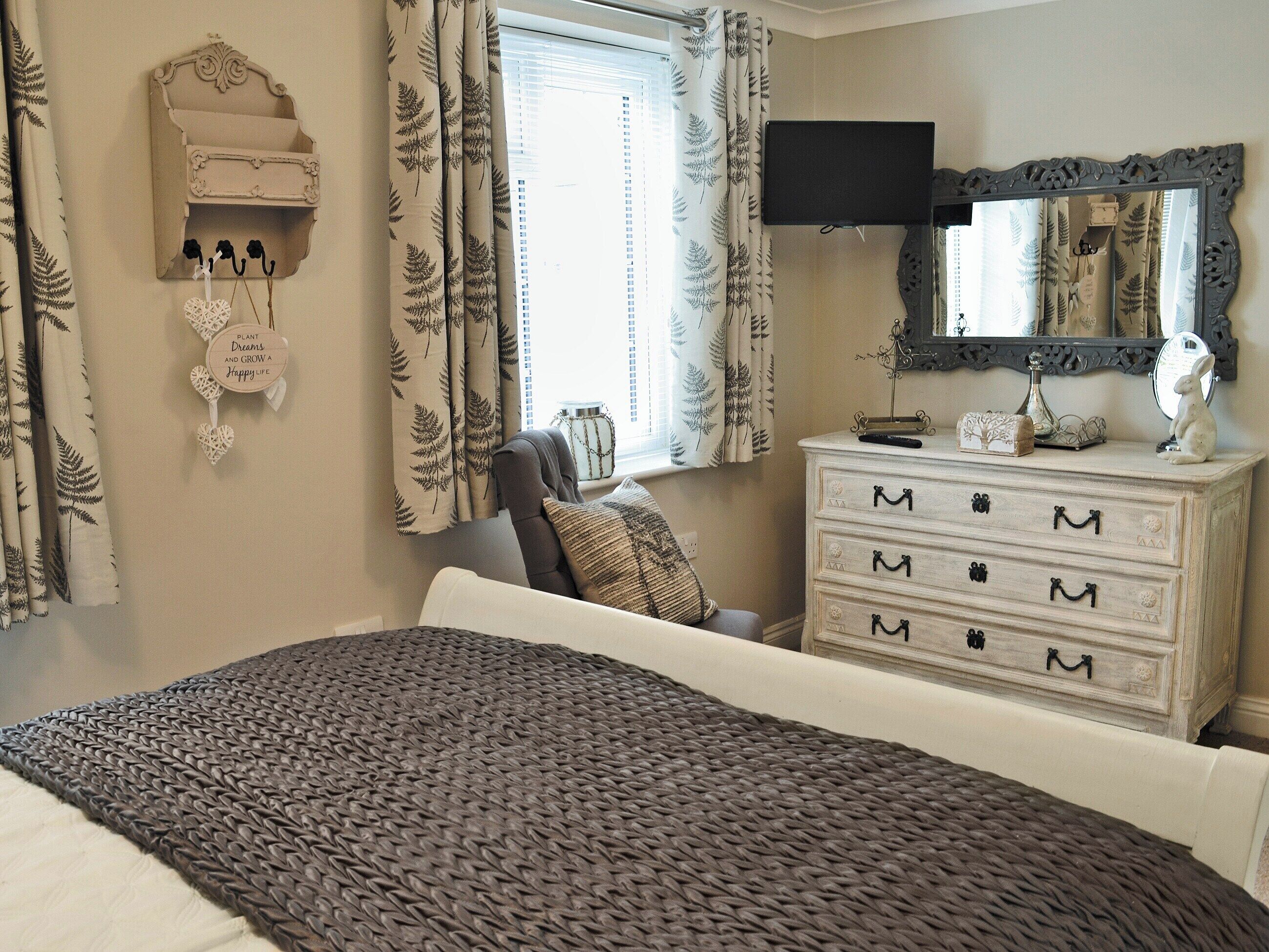 A bedroom with a bed, dresser, television, and a decorative wall piece.