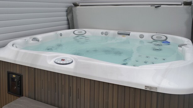 A hot tub with a control panel, surrounded by wooden paneling.