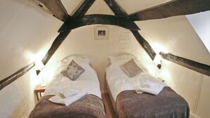 A room with two beds under a sloped ceiling with exposed beams.