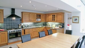 A modern kitchen with wooden cabinets, a large island, and a dining area with chairs.