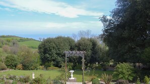 A garden with a pergola, a white statue, and a variety of plants. - 2 bedroom accommodation in Maidencombe, near Torquay (Maidencombe, near Torquay)