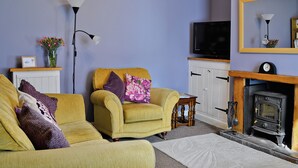A living room with a yellow armchair, a fireplace, and a television. - 2 bedroom accommodation in Winterton-on-Sea, near Great Yarmouth (Winterton-on-Sea, near Great Yarmouth)