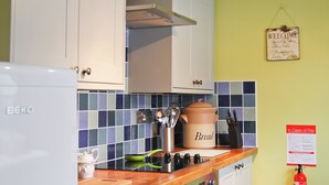 A kitchen with white cabinets, a BEKO refrigerator, a bread cooker, and a fire safety notice. - 2 bedroom accommodation in Winterton-on-Sea, near Great Yarmouth (Winterton-on-Sea, near Great Yarmouth)