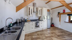 A kitchen with wooden beams, a stainless steel sink, a built-in oven, and a refrigerator.