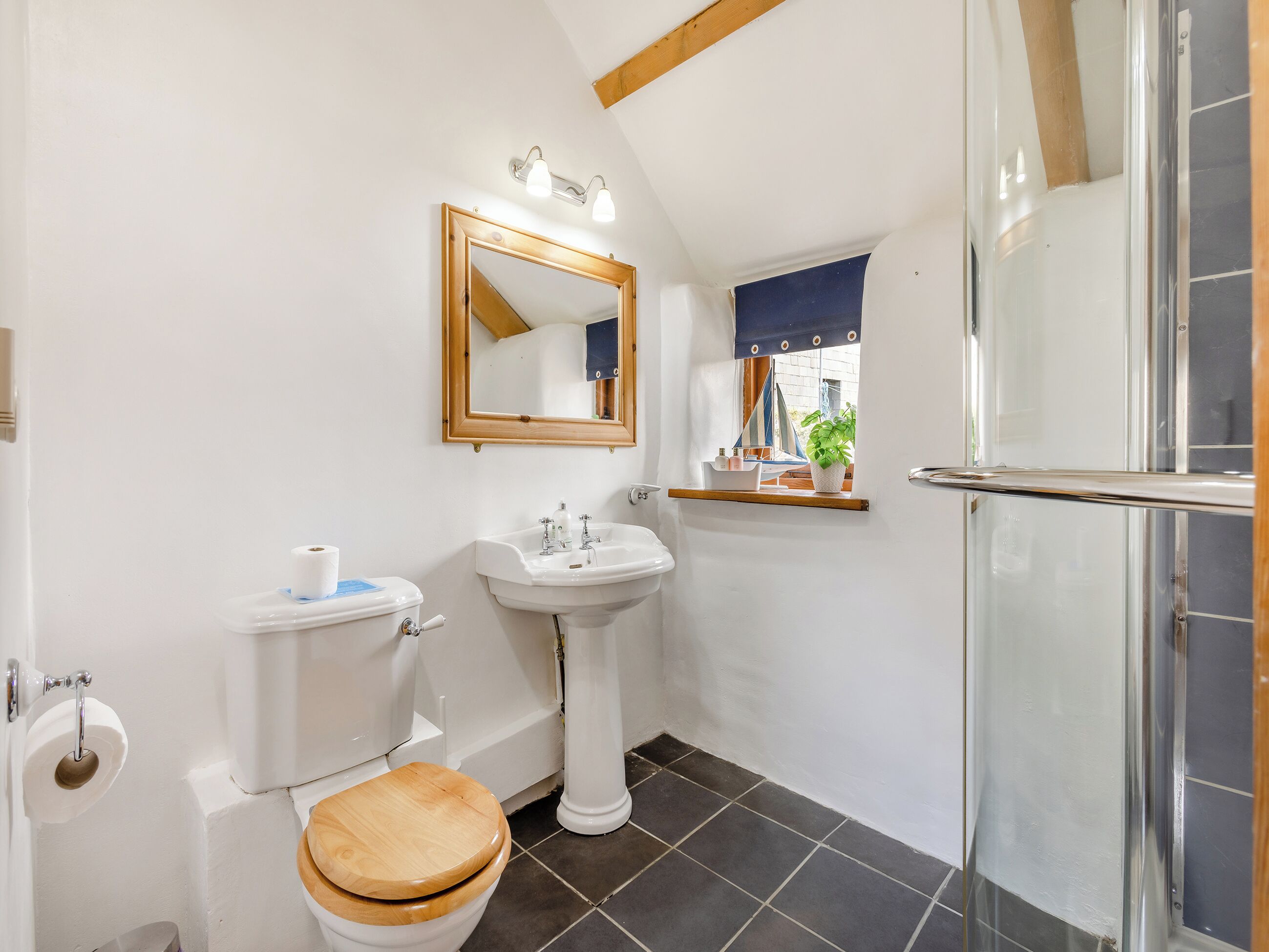 Ein Badezimmer mit Toilette, Waschbecken, Spiegel und einem kleinen Fenster mit Blick.