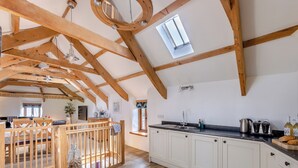 A spacious kitchen with wooden beams, a large window, and a built-in island with a sink and countertop.