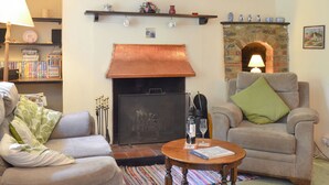 A living room with a fireplace, a sofa, a coffee table, and a bookshelf. - 3 bedroom accommodation in Passfield Common, near Liphook (Passfield Common, near Liphook)