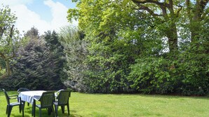 An outdoor seating area with a table and chairs, surrounded by lush greenery and trees. - 3 bedroom accommodation in Passfield Common, near Liphook (Passfield Common, near Liphook)