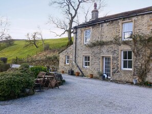 A stone building with a gravel driveway, a wooden chair, and potted plants. - 3 bedroom accommodation in Scalegill, near Kirkby Malham (Scalegill, near Kirkby Malham)