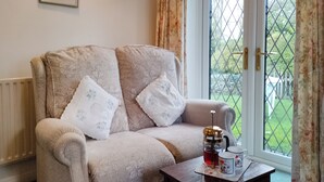 A cozy room with a sofa and a table with a coffee pot and cups.
