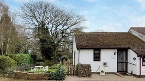 A small, white building with a tiled roof, a stone wall, and a wooden fence.