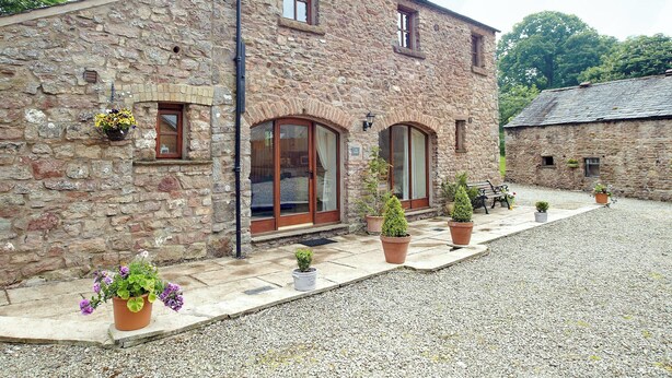 A stone building with large windows and a gravel driveway.
