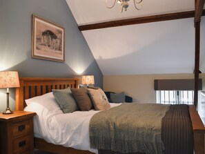 Un dormitorio con cama de madera, dos lámparas de noche, un cuadro en la pared y una ventana con persianas.