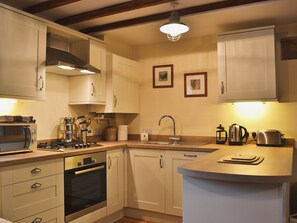 A kitchen with white cabinets, a Bosch oven, a sink, and a wooden countertop.
