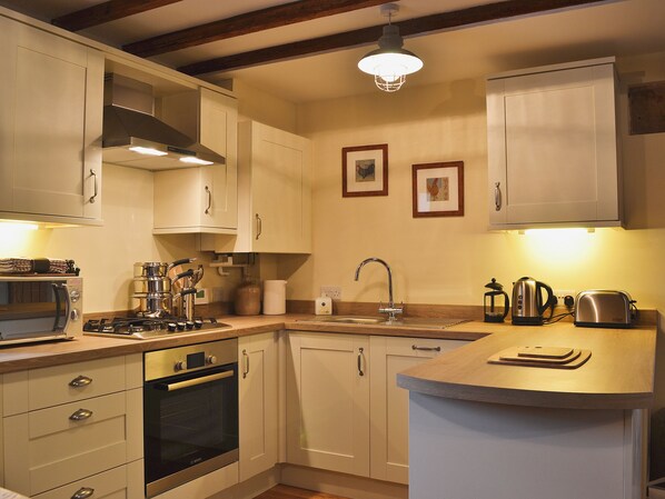 A kitchen with white cabinets, a Bosch oven, a sink, and a wooden countertop.