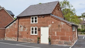 A two-story stone building with a white door and windows, a parking lot in front, and a tree to the right. - 2 bedroom accommodation in Myddle, near Shrewsbury (Myddle, near Shrewsbury)