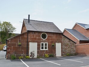 A stone building with a pitched roof, a chimney, and a small circular window.