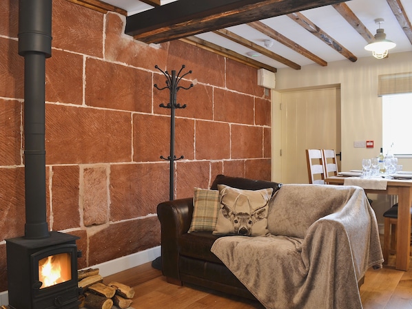 A cozy living room with a fireplace, a wooden table set for dining, and a brick wall.