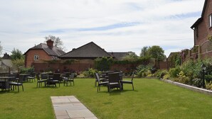 A garden with a paved walkway leading to a seating area with chairs and tables. - 2 bedroom accommodation in Myddle, near Shrewsbury (Myddle, near Shrewsbury)
