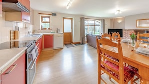 A spacious kitchen with modern appliances, a dining area with wooden furniture, and a large window providing natural light. - 2 bedroom accommodation in Alston (Alston)