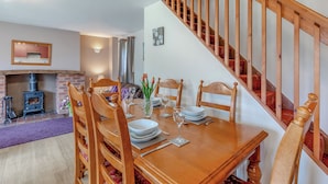 A dining area with a wooden table set for four, surrounded by wooden chairs. A staircase with wooden railings is visible to the right. - 2 bedroom accommodation in Alston (Alston)