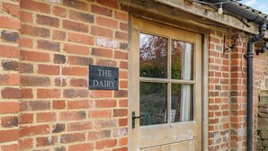 A brick building with a wooden door and a sign reading 'THE DAIRY'.