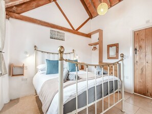 A bedroom with a bed, wooden ceiling beams, a hanging light fixture, a wooden door, and a mirror. - 1 bedroom accommodation in Arlingham, near Frampton-on-Severn (Arlingham, near Frampton-on-Severn)