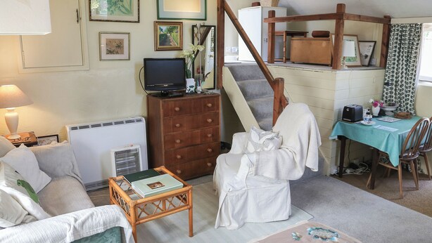 A cozy living room with a sofa, a small table, a chair, a staircase, and a dining area with a table and chairs. - 0 bedroom accommodation in Pilton, near Glastonbury (Pilton, near Glastonbury)