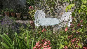 A garden with a round glass table and two white chairs. - 0 bedroom accommodation in Pilton, near Glastonbury (Pilton, near Glastonbury)