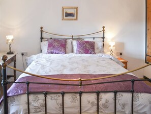 A bed with a metal frame, white bedding with floral patterns, and two bedside lamps. - 3 bedroom accommodation in Trebarwith, Delabole (Trebarwith, Delabole)