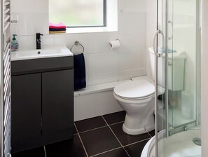 Een badkamer met een wit toilet, een wastafel en een douchecabine van glas.
