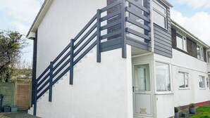 A two-story house with a white exterior, a dark staircase, and a small balcony.