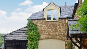 A stone building with a beige door, a window, and a garage. - 1 bedroom accommodation in Upper Brailes, near Banbury (Upper Brailes, near Banbury)