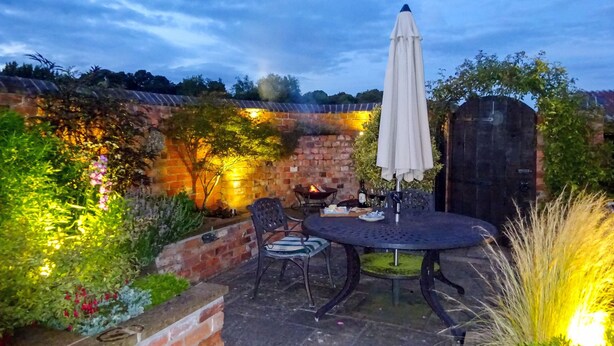 An outdoor patio with a round table, chairs, and a large umbrella. - 1 bedroom accommodation in Upper Brailes, near Banbury (Upper Brailes, near Banbury)