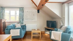 A living room with a blue sofa, a wooden coffee table, a television, and a radiator. - 1 bedroom accommodation in Upper Brailes, near Banbury (Upper Brailes, near Banbury)