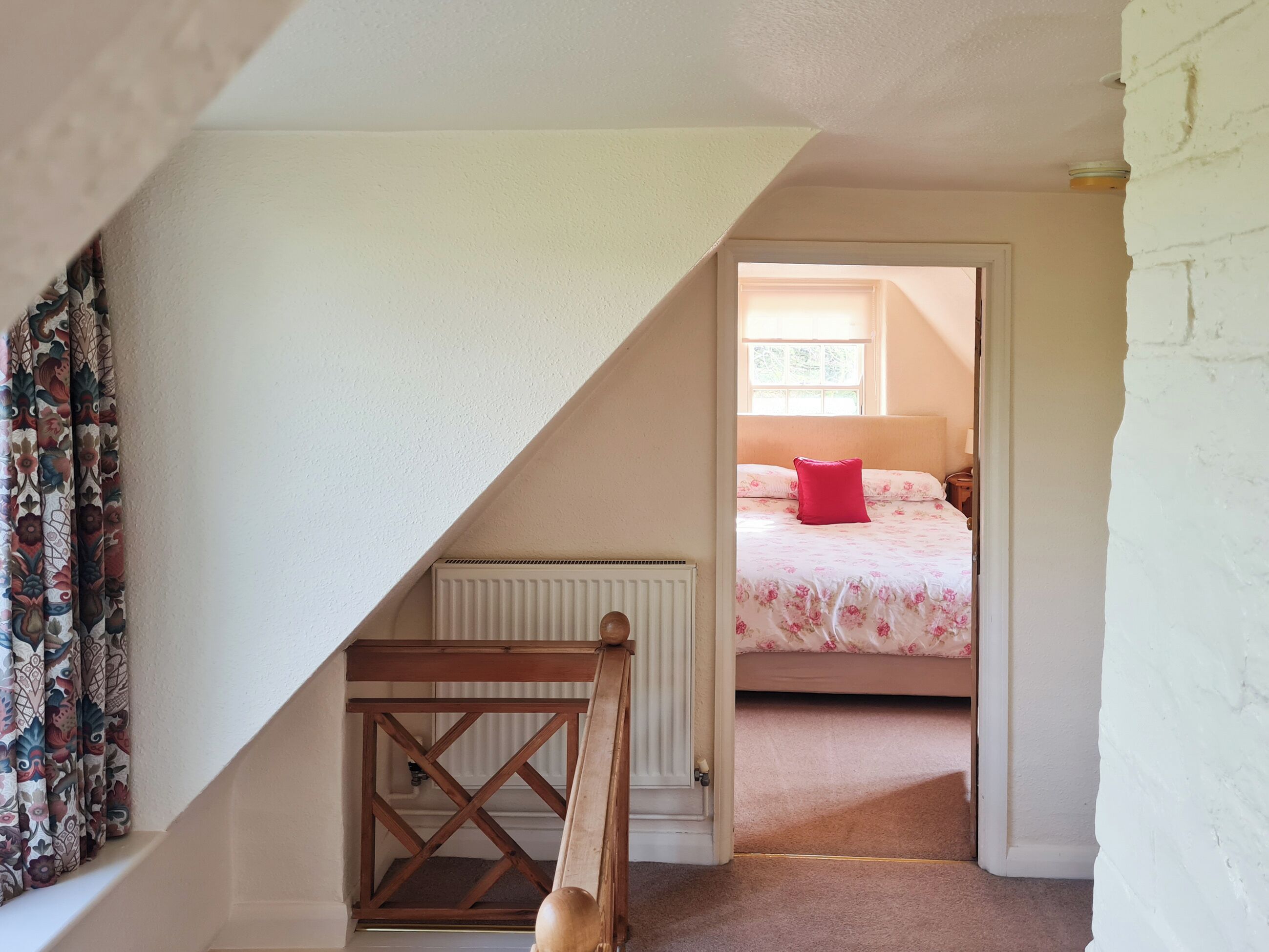 A bedroom with a bed, a radiator, and a wooden chair.