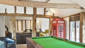 A pool table in a room with exposed wooden beams, a red telephone booth, and a leather armchair. - 5 bedroom accommodation in Botesdale, near Diss (Botesdale, near Diss)