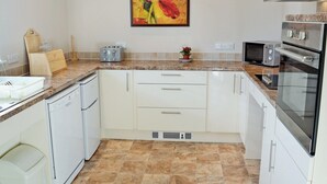 A modern kitchen with white cabinets, a granite countertop, a toaster, a microwave, and an oven.