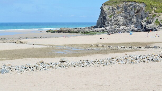 A beach with rocky outcrops and a cliff.