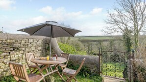 A stone wall with a table and chairs under an umbrella, a stone pathway, and a metal gate. - 3 bedroom accommodation in Hartland, near Bideford (Hartland, near Bideford)