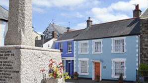 A stone monument with names inscribed, a blue building with white trim, and a clear sky. - 3 bedroom accommodation in Hartland, near Bideford (Hartland, near Bideford)