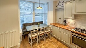 A kitchen with a dining table, chairs, a bench, a hanging light, and a stove. - 3 bedroom accommodation in Keswick (Keswick)