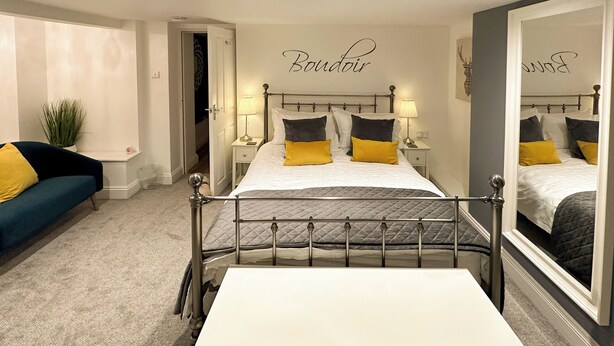 A bedroom with a bed, bedside tables, a mirror, a sofa, and a potted plant. - 3 bedroom accommodation in Keswick (Keswick)