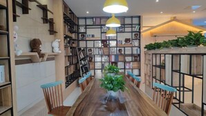 Un espace repas avec une longue table en bois, des chaises et une plante en pot placée au centre.